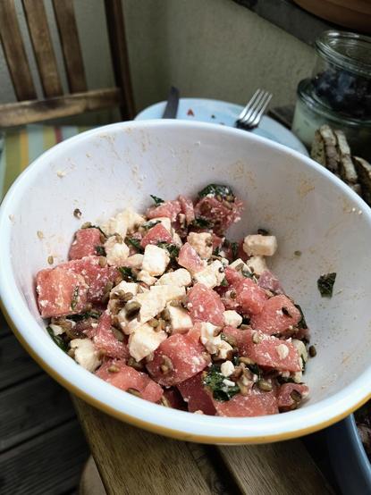 Eine Schüssel mit Feta, Melone, Minze, gerösteten Sonnenblumenkernen, etwas Zitronensaft, Olivenöl und Salz