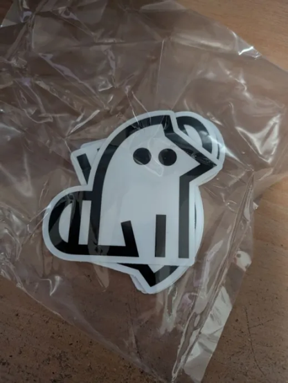 10 stickers of the sitelen pona glyph "kijetesantakalu" stacked on top of eachother contained in a plastic bag.