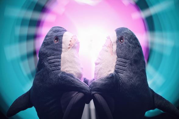 Two Blahaj's on chairs facing each other, lit by cyan, pink and white light streaks