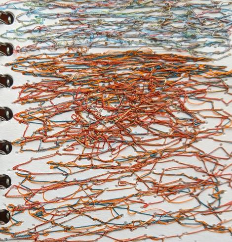 A mass of threads, quite messy and random. A mixture of oranges, reds, pale blues and greys. Abstracted beach textures with the sea beyond.