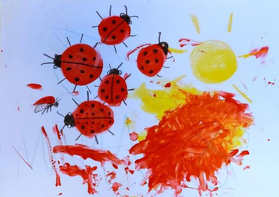 Large sheet of paper filled with scribbles and finger-painting tempera splotches in red and yellow. There are 5 red ladybugs, a yellow sun, and a large area of messy paint.