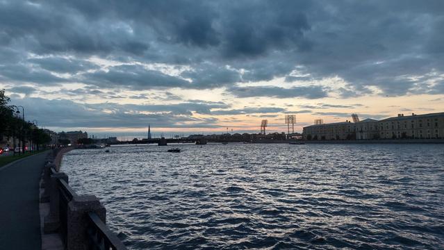 Вечерний вид на Неву и Тучков мост с набережной Макарова в Питере. Небо затянуто облаками, но ближе к горизонту с прояснениями и освещением белых ночей.