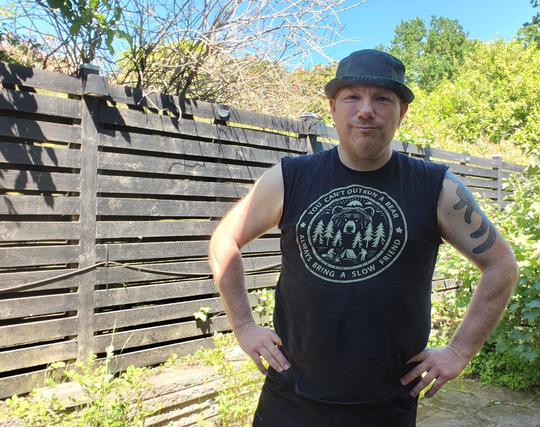 Me (white male in his early 50s) in my garden with a black tshirt, sleeves torn off because of the heat, wearing a terrible greyish beanie to protect my bald head from the sun. Tshirt days: you can't outrun a bear. Always bring a slow friend.