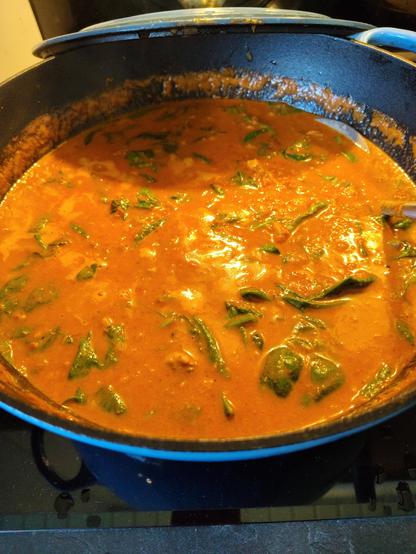 A creamy orange curry with spinach leaves