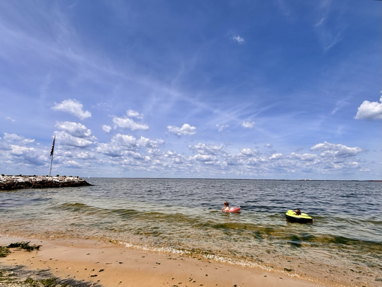 Blue skies over the Chesapeake bay. Two people floating on inner tubes on the water