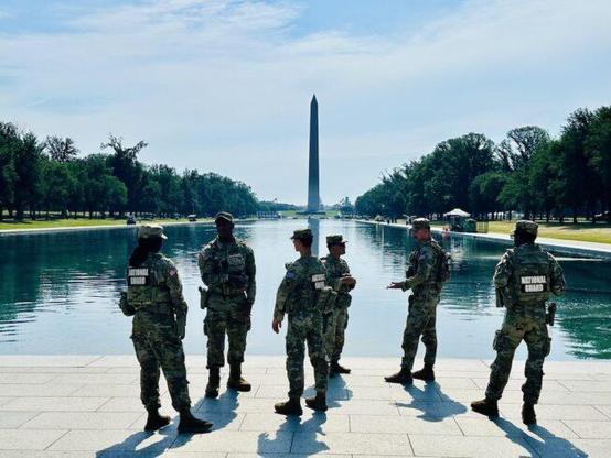 Photo of 6 National Guards at the edge of the reflecting pool with the Washington Monument in the distance.