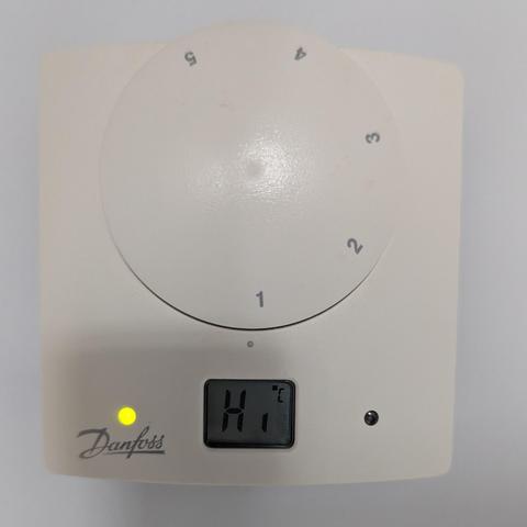 A thermostat on a wall. On the bottom of it, a small LCD 8 segment display. Instead of showing a 2 digit number, it just says "Hi"