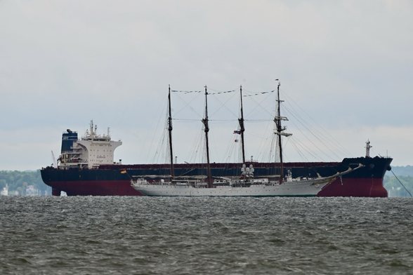 The tall ship Juan Sebastian de Elcano from Spain sailing in front  of a tanker anchored in the Chesapeake Bay.