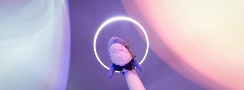 Smolhaj (small IKEA shark) with a bow tie under a halo streaked by blue and orange light