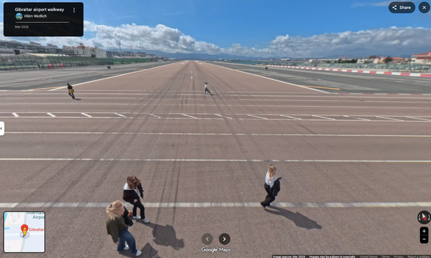 A photograph taken from the middle of the runway, showing people walking across.