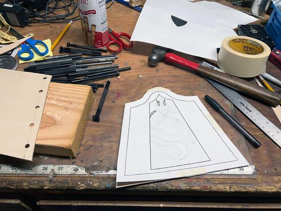 A hand-drawn paper guide lies among tools and materials on a very cluttered workbench.