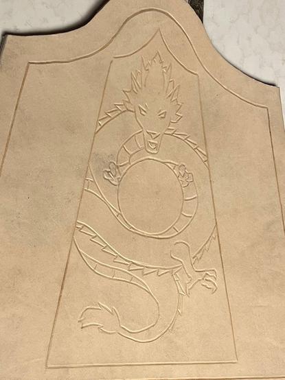 A dragon and pattern have been cut/imprinted into the leather, which has been trimmed to the final outline.