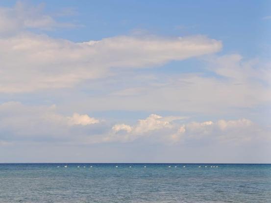 Blick auf das ruhige Meer unter blauem Himmel mit leichter, weißer Bewölkung