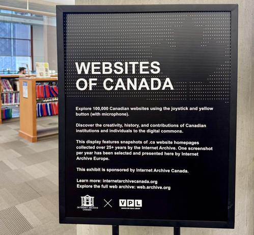 Close-up of the "Websites of Canada" exhibit sign at the Vancouver Public Library, on a black board with white text explaining that visitors can explore 100,000 Canadian websites using a joystick and microphone button. The sign describes the display as featuring snapshots of .ca homepages collected over 25+ years by the Internet Archive, sponsored by Internet Archive Canada, with logos for Internet Archive Canada and Vancouver Public Library at the bottom.