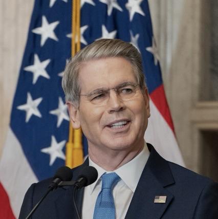 Treasury Secretary Scott Bessent looking smug standing at a microphone.