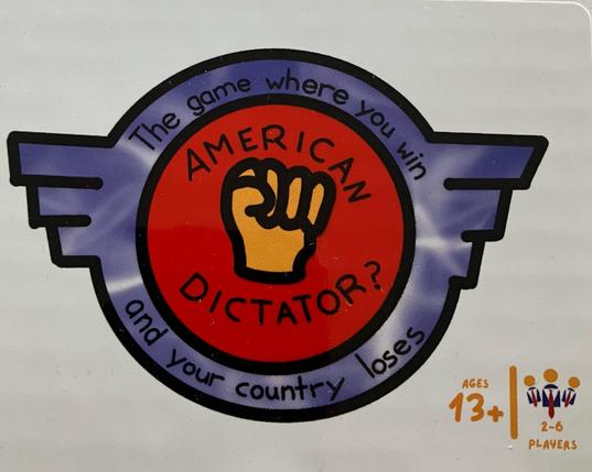Label on a board game. A crest with an orange clenched fist inside a red circle with the name of the game, “American Dictator?”, around it. The red circle is within a purple, winged, circle containing the phrase “The game where you win and your country loses”