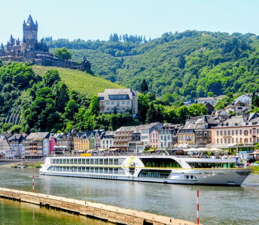 Op deze foto is een cruiseschip te zien, die vaart in rivier de mosel, verder nog links boven de burcht van Cochem, en een aantal mooie huizen. Naast de burcht op de foto nog veel groene natuur.