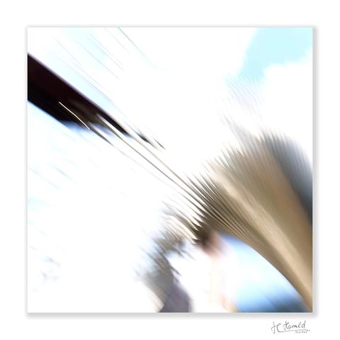 A square image with white frame and a white background. Blurred lines run diagonally across the picture. From the top left, one thick and several thin black lines extend towards the centre of the picture. In the top right-hand corner is a pale blue patch. From the bottom right, golden-brown lines fan out across the picture, forming a jagged edge at the end. Below these are areas of grey, blue and white. 

This image is protected by copyright and may not be used without my permission – particularly not for AI training purposes.