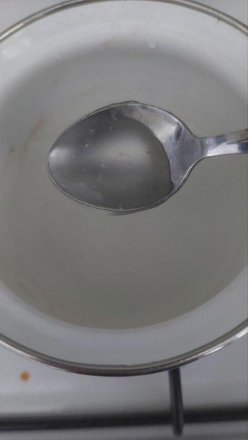 Close up of the pot, with a spoon showing the clear gel obtained by mixing potato starch and water.