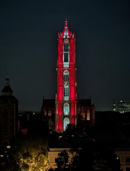 Red-white-red lit church tower at night.