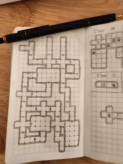 Picture of a pocket notebook with grid paper, and a pencil drawing of a dungeon map with interconnected rooms and hallways.