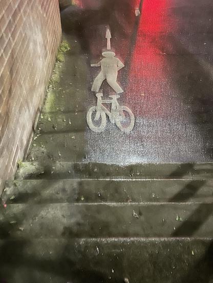 Night time photo of a bike lane with a staircase in the middle of it.