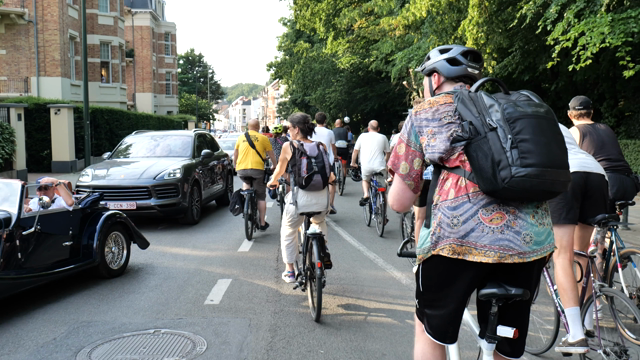 Video of the Critical Mass movement. Large crowd of cyclists passing by a lane of cars whose movement has halted because of it.