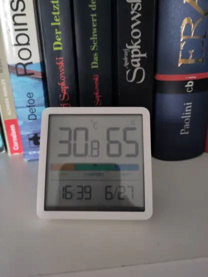 A digital thermometer and hygrometer showing 30.8°C and 65% humidity at 16:39 UTC+1.