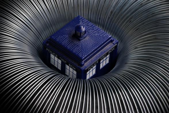 The TARDIS, a blue police phone box, engulfed in a silvery metal donut, looking like it's being sucked into a time vortex.