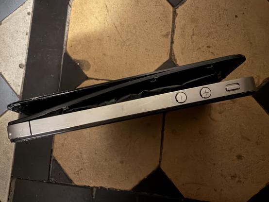 An iPhone 4S that has split open due to a swollen battery.