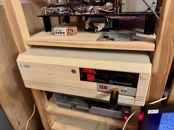 This is a picture of an Amiga 4000 in a nice IKEA wood shelf with a plastic-less Mac Quadra 630 below it and a Mac Quadra 610 in a caseless motherboard mount above it.
In the corner one can see the corner of the AmigaOS screen where booting was interrupted so a new kernel could be copied.
The Amiga has a Gotek installed, and a USB stick is inserted. The track display shows "36".