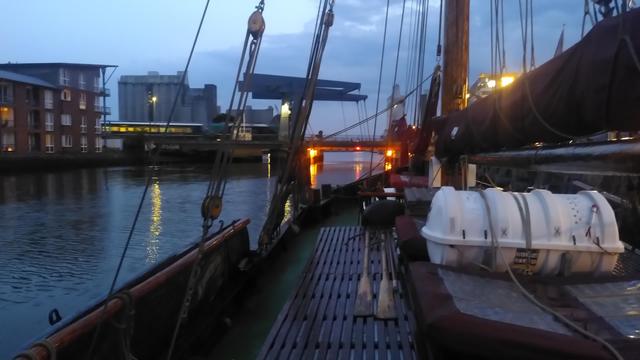 Husumer Innenhafen, Blick nach vorne vom Deck der Windsbraut, einem Elbewer. Zwischen Großmast auf der rechten Seite und stehendem Gut fährt eine Siemens Eurorunner Diesellokomotive mit einem Regionalexpress im kleidsamen Nah.SH Petrol und Blau über die Klappbrücke Richtung Sylt.