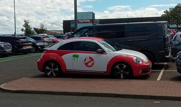 A VW beetle painted red and white, with the Ghostbusters logo on the door and globs of ectoplasm green spattered around.