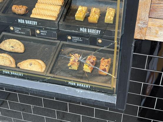 the glass window outside the Mòr Bakery is cracked. the point of impact is precisely in front of the display of “rhubarb & strawberry slices”
