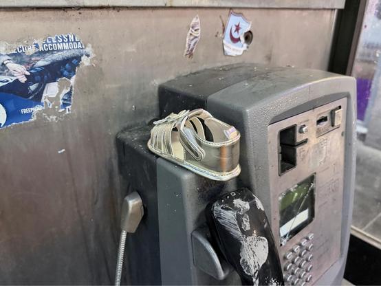 a single baby shoe has been abandoned on top of a payphone