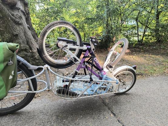 Ein Fahrrad mit BobYak Fahrradanhänger. Darauf befindet sich ein Kinderfahrrad auf dem Kopf stehend - Nahaufnahme