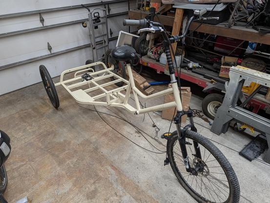 The full cargo trike. The brake cables are hanging loose, but otherwise it looks mostly assembled. The frame is now a creamy white, instead of the terrible mint green it used to be.