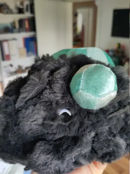 A side view of the crystal lizards head.
It has a tiny eye which is mostly black, but has a thin white border around the upper half of the circle, suggesting the lizard has an actual eyeball with sclera.
I think it resembles the side eye dogs sometimes give people, where the visibke parts are mostly black but you can see a bit of their sclera (white part).