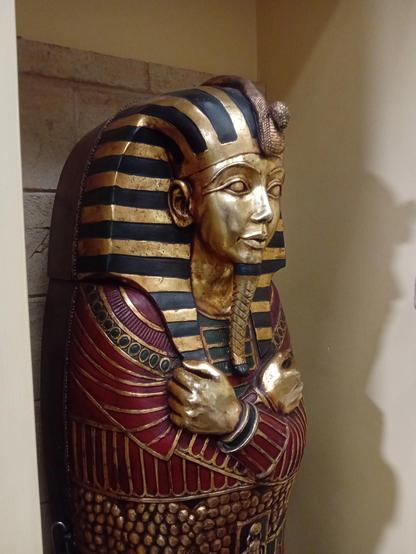 A red, black and gold-painted pretend Egyptian sarcophagus in an alcove. The sign next to it (not pictured) shows it in situ next to Nicholas Cage in said film for its very brief appearance.