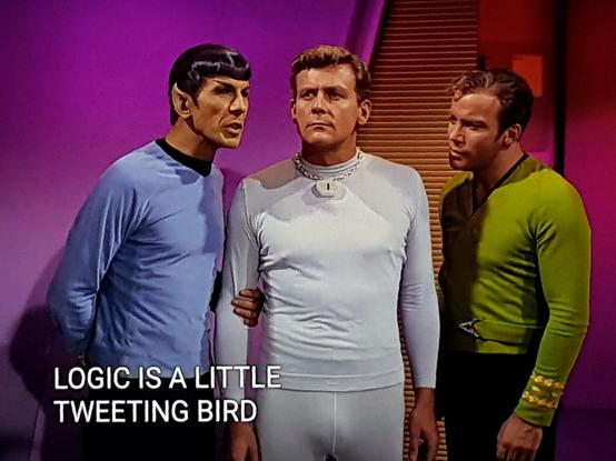 Star Trek The Original Series scene. We're on planet somewhere and in a room backlit in purple and red. There's a human looking man standing and looking off in the distance with a determined face. He's wearing a snug white long sleeve shirt and white spandex pants that fit a bit too tight if you ask me. Definitely rocking some moose knuckle. Kirk and Spock are standing on either side of him, Spock is holding his arm and leaning in as if whispering sweet nothings in his ear. Closed caption reads, "Logic is a little tweeting bird."
