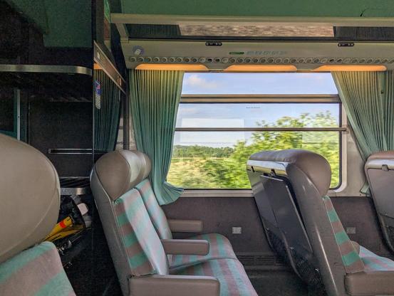 View across the aisle in a Corail carriage. Comfy seats in the red-grey moquette. A Birds folding bike is stored in the luggage rack to the left.