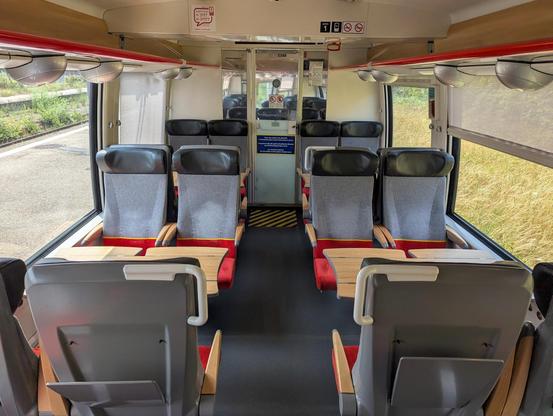 The interior of the first class compartment in a refurbished AGC. Grey-red seats.