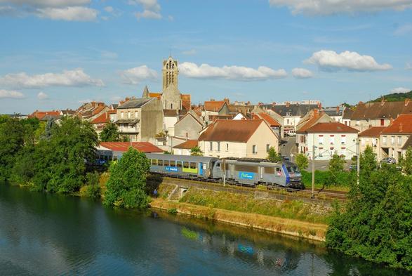 A small village with an old church behind a railway line along a river. A silver-blue Sybic in Grand-Est livery passes with a Corail train. The colours look delightfully warm and a bit retro - it's the out-of-camera JPG from a 20 years old Nikon.