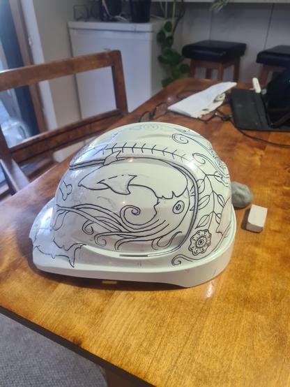 White industrial hard hat with giant squid and floral motif in the style of scrimshaw drawn on it.