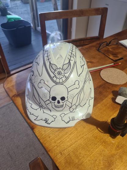 White industrial gard hat with skull and crossbones flanked by hammerhead sharks and floral motifs in scrimshaw style.