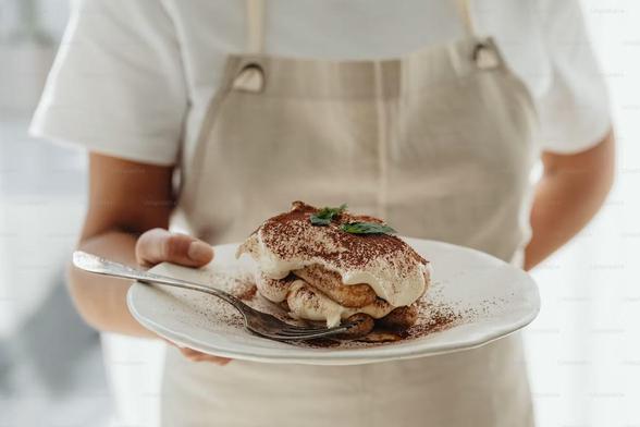 A person holding a plate with a fantastic portion of tiramisu, credit Karolina Grabowska
