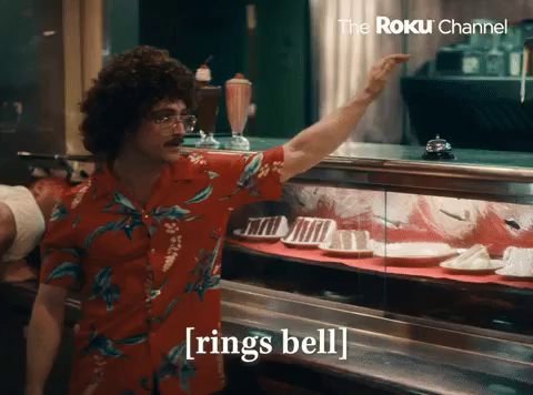 Daniel Radcliffe playing Weird Al Jankovic.
He hits a bell on the deli counter, then steps away saying “Order Up.”