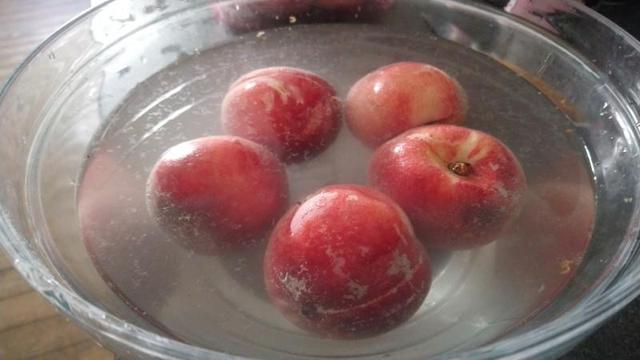 A bowel of corporate peaches in a solution of water and baking soda. A disgusting film floats on the surface.