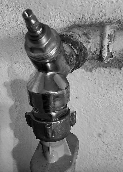 Picture of an old watervalve with the handle broken off. The chrome of the valve shines nicely. The iron of the pipe is corroded and painted over with whitewash. A lot of adapters are used to make the assembly work