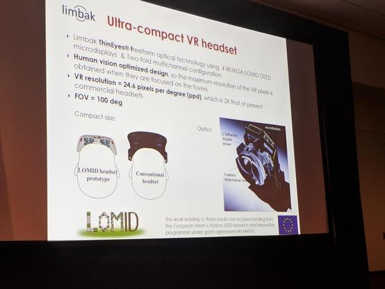 Photograph of a slide titled: Ultra-Compact VR Headset. The thin-eyes display consists of doublet-lenses bonded to a microOLED display. Some key specs shown: 24.6 pixles per degree with a FOV of 100 degrees. The diagram shows the headset is half the thickness of the HTC VIVE.